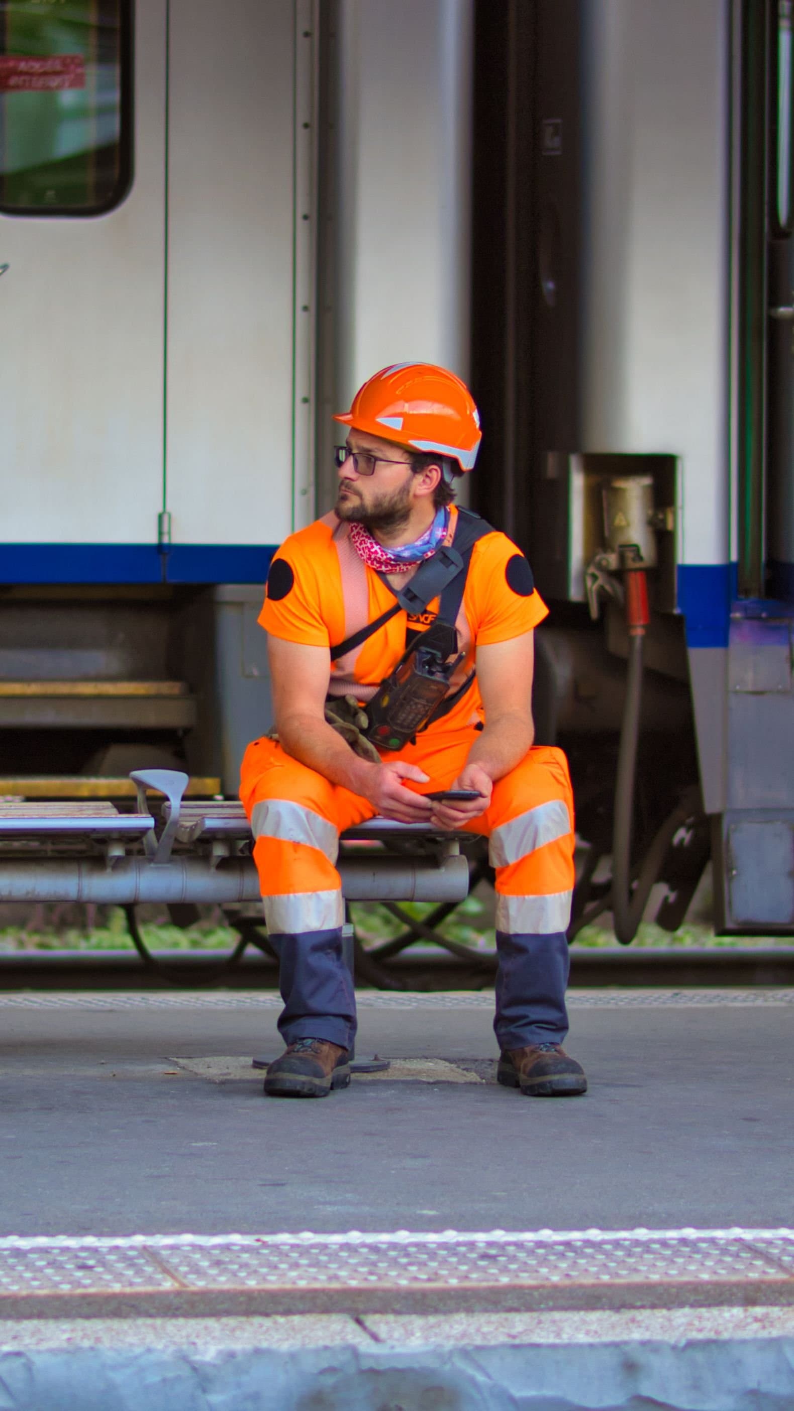 Ouvrier en tenue haute visibilité et casque de chantier consultant son smartphone lors d’une pause